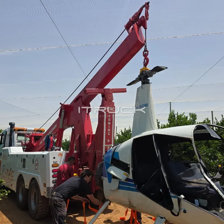 Integrated wrecker boom lifting a damaged helicopter on site
