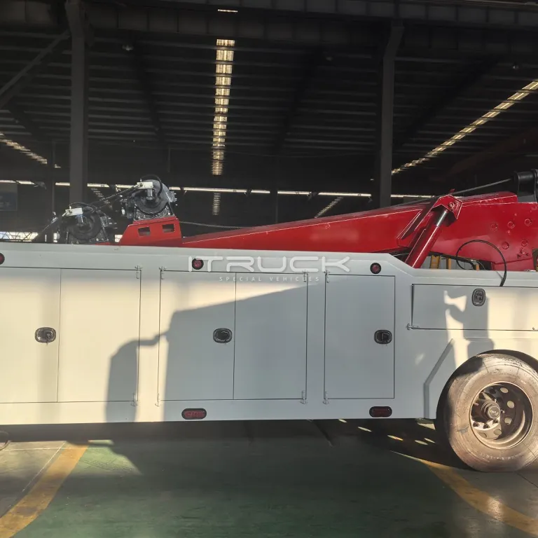 Side view of white wrecker body with red boom on chassis