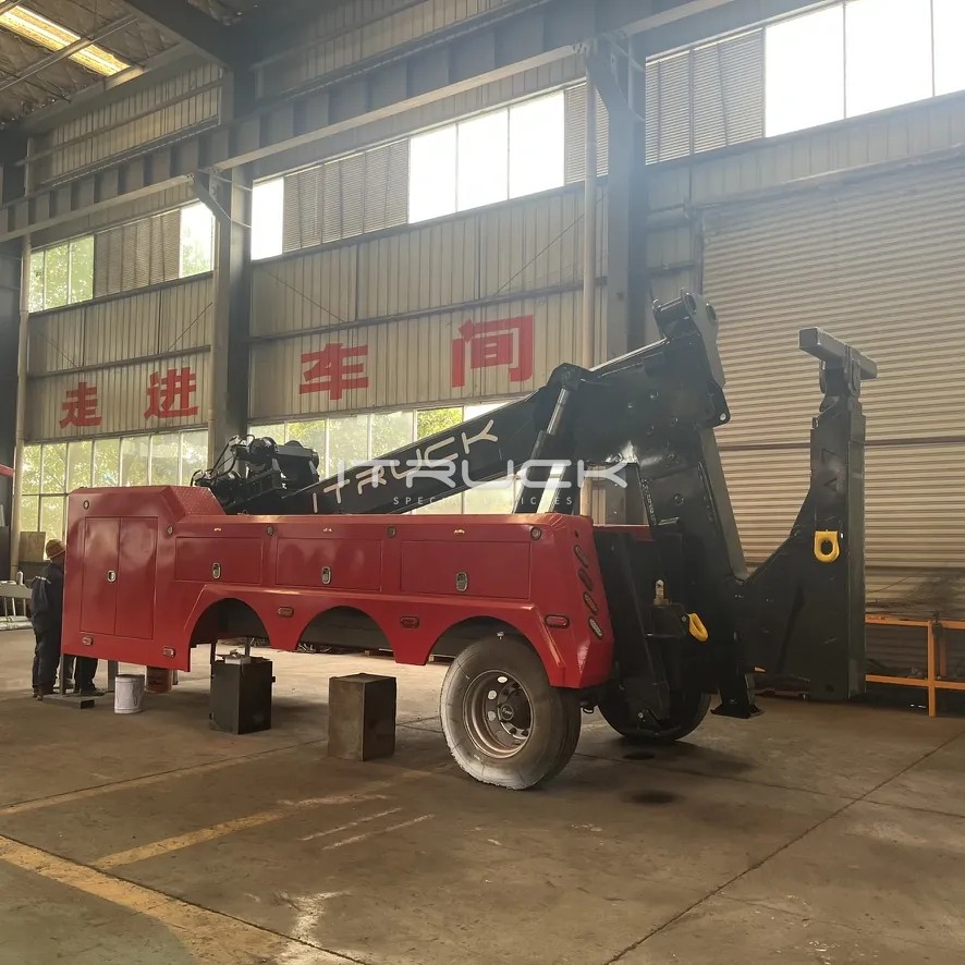 Red and black integrated wrecker with boom raised on chassis